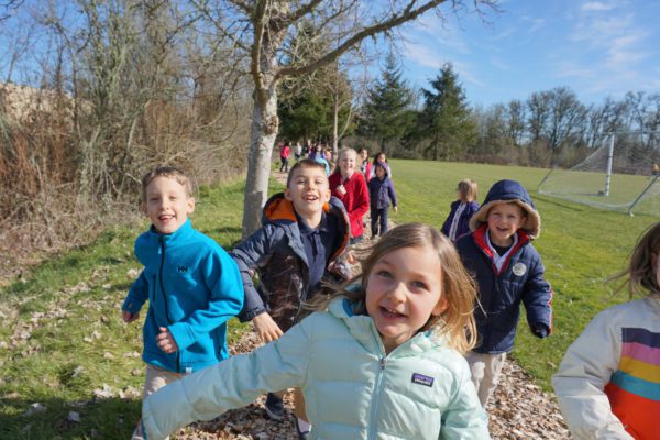 Children running through the grounds of Ashbrook Independent School toward the camera