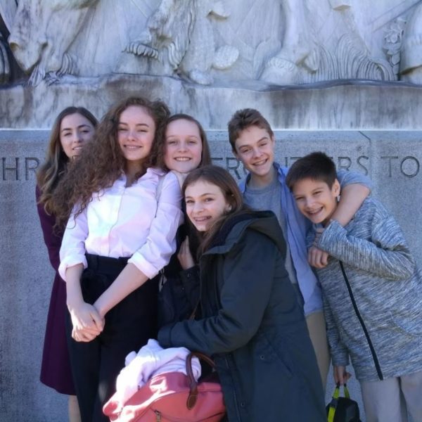 A group of eighth graders pose in front of a statue in Seattle